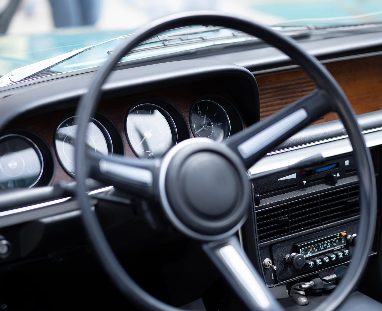 The chrome badge and paint of a classic car on a showroom floor.
